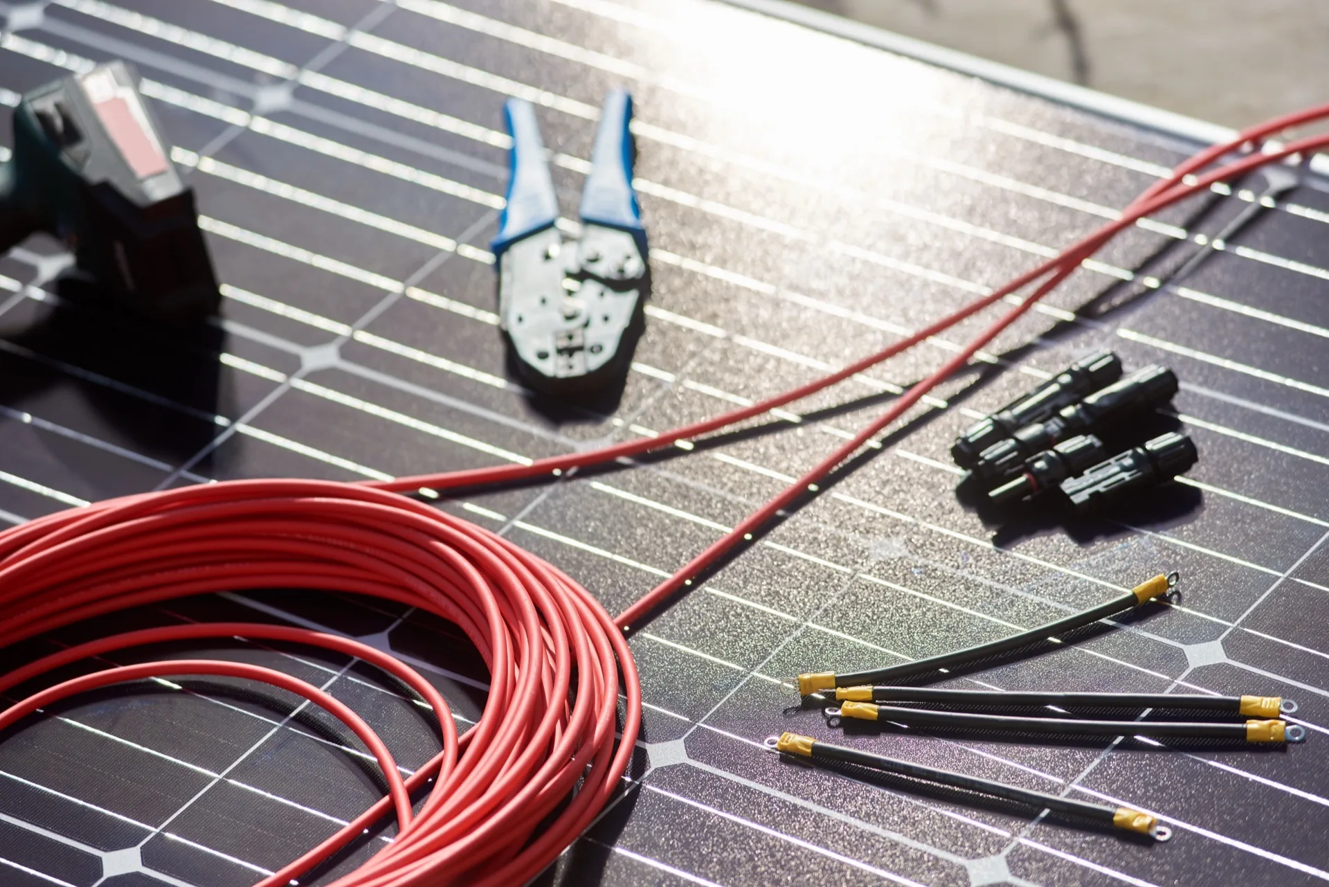 Solarkabel, Steckverbinder, Kabelschuhe und Werkzeug auf einem Solarmodul